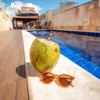 A poolside setting with a coconut drink and sunglasses on a marble surface.
