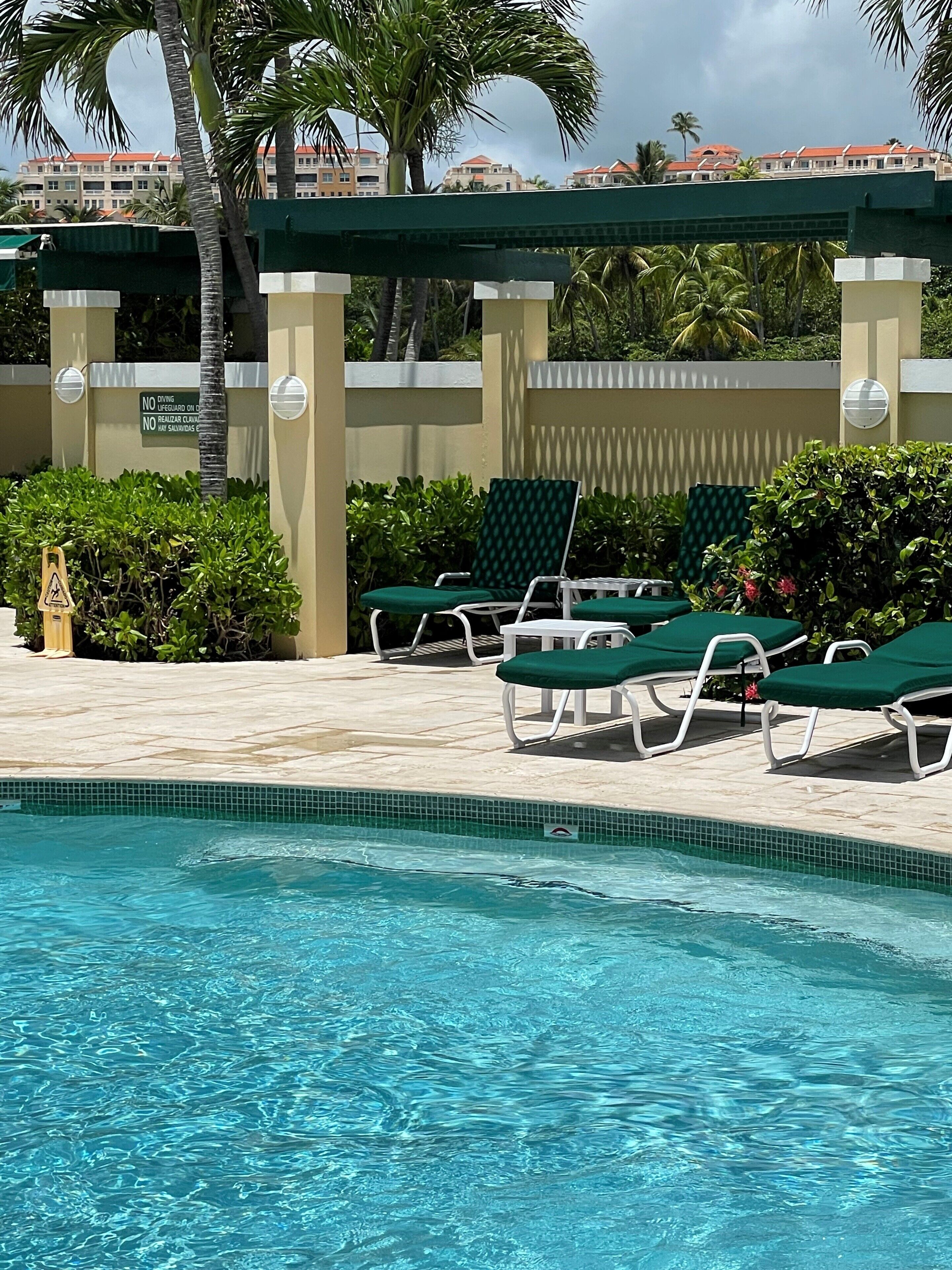 Un espace piscine avec des chaises longues et un panneau indiquant qu’il est interdit de plonger.