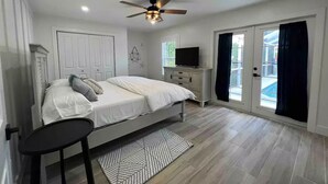 A bedroom with a bed, a dresser, a TV, and a ceiling fan.