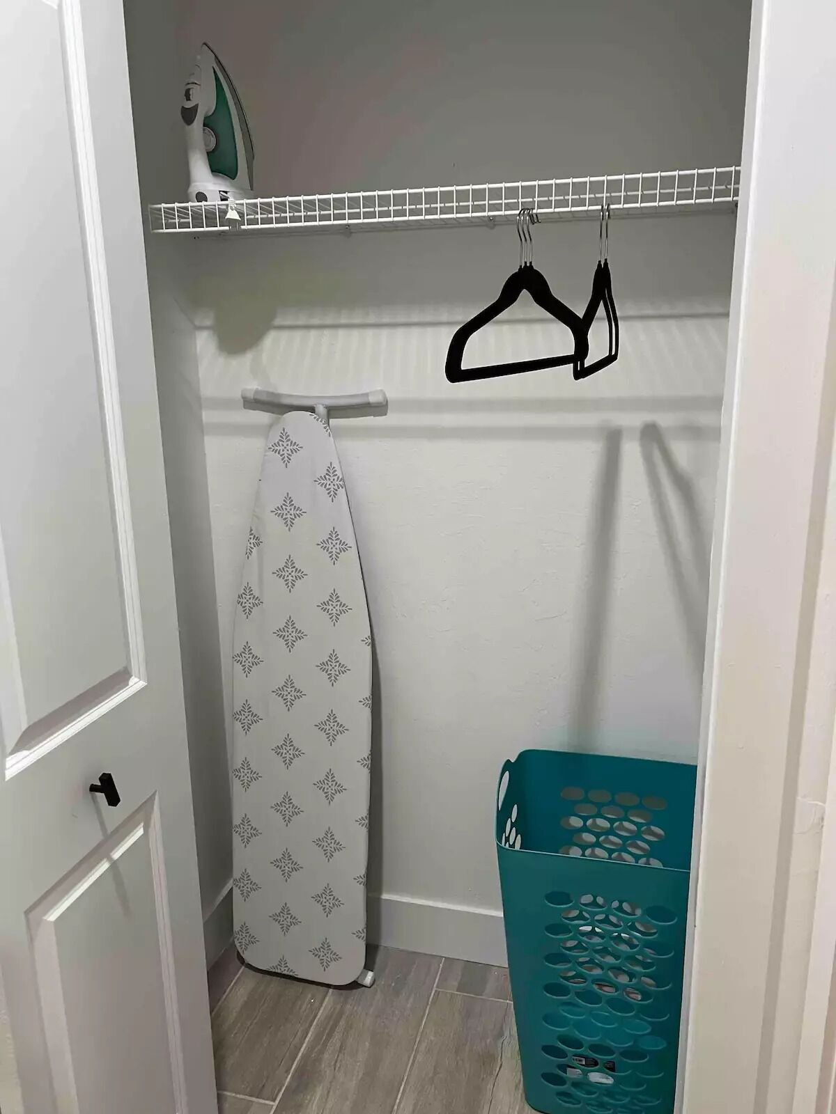 Une buanderie équipée d’un étendoir, d’une planche à repasser et d’un panier à linge.