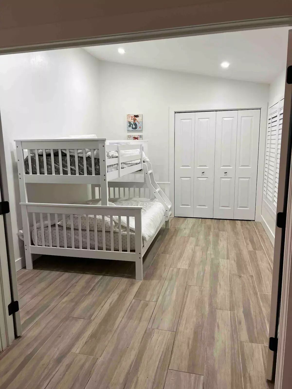 A room with a bunk bed, a wardrobe, and a door.
