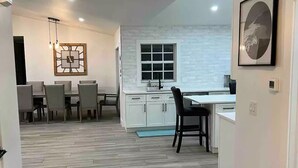 A modern kitchen with white cabinets, a window, and a dining area with chairs and a table.
