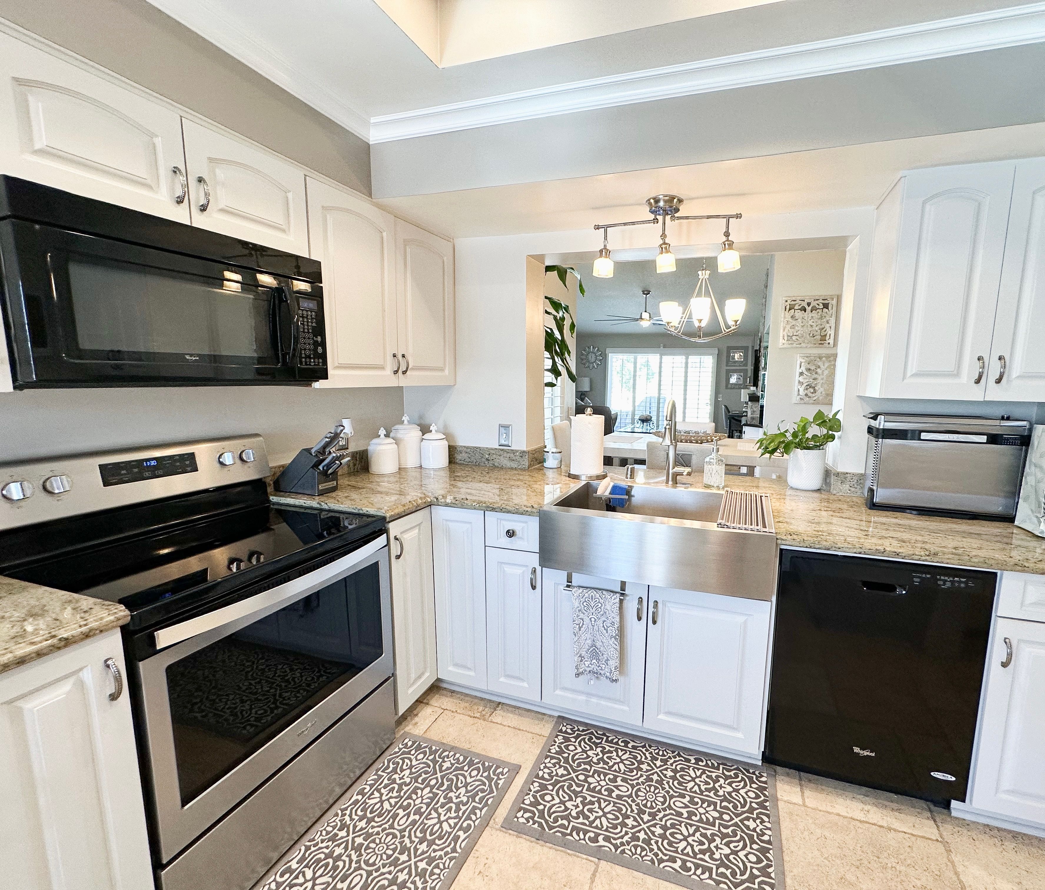 A modern kitchen with white cabinetry, stainless steel appliances, and a central island.