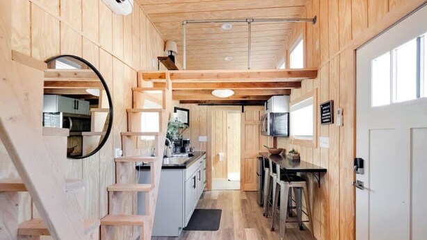 A compact kitchen with wooden walls, a central island, and a small dining area. - Tiny Home Sleep 4 PALO DURO CANYON Base Camp WTAMU (Canyon)