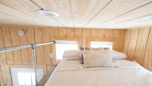A wooden-paneled room with a bed, a window, and a door. - Tiny Home Sleep 4 PALO DURO CANYON Base Camp WTAMU (Canyon)