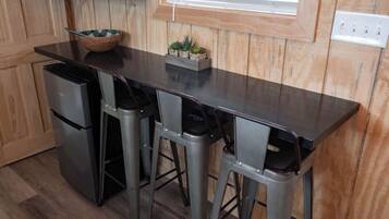 A kitchen with a dark countertop, four bar stools, a small wooden bowl, and a planter with succulents.