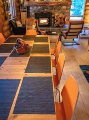 A cozy cabin interior with a fireplace, wooden flooring, and a seating area with orange chairs. - The Timberline Romance (Golden)