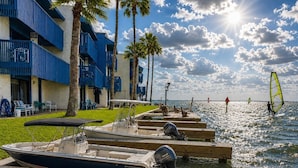Een pand aan het water met boten in de haven, een strand en blauwe balkons.