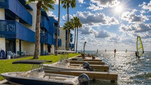 Une propriété située au bord de l’eau, avec des bateaux amarrés, une plage et un bâtiment doté de balcons bleus.