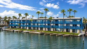 Un hôtel situé au bord de l’eau, doté de nombreux balcons, d ’un port de plaisance et de palmiers.