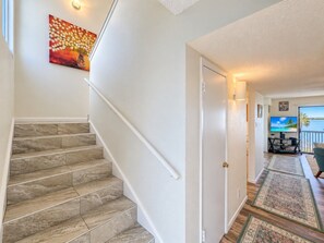 A staircase with a handrail, a door, and a living area with a television and a view of the outdoors.