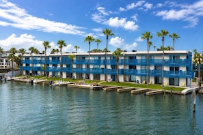 A waterfront hotel with multiple balconies, a marina, and palm trees.