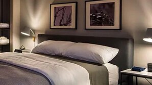 A modern hotel room with a large bed, a bedside table with a lamp, and two framed artworks on the wall. - Westwood Living - Gorgeous Modern One Bedroom Available For Rent, Close to UCLA (Los Angeles)