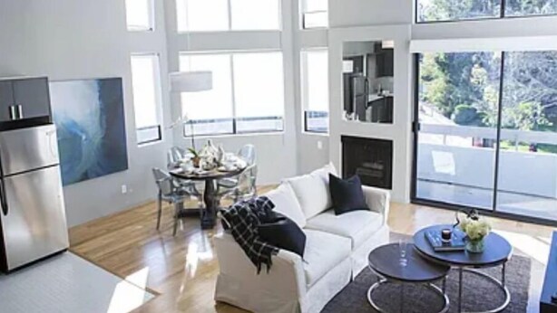 A modern living room with a white sofa, a dining table, and a kitchen area with a refrigerator. - Westwood Living - Gorgeous Modern One Bedroom Available For Rent, Close to UCLA (Los Angeles)