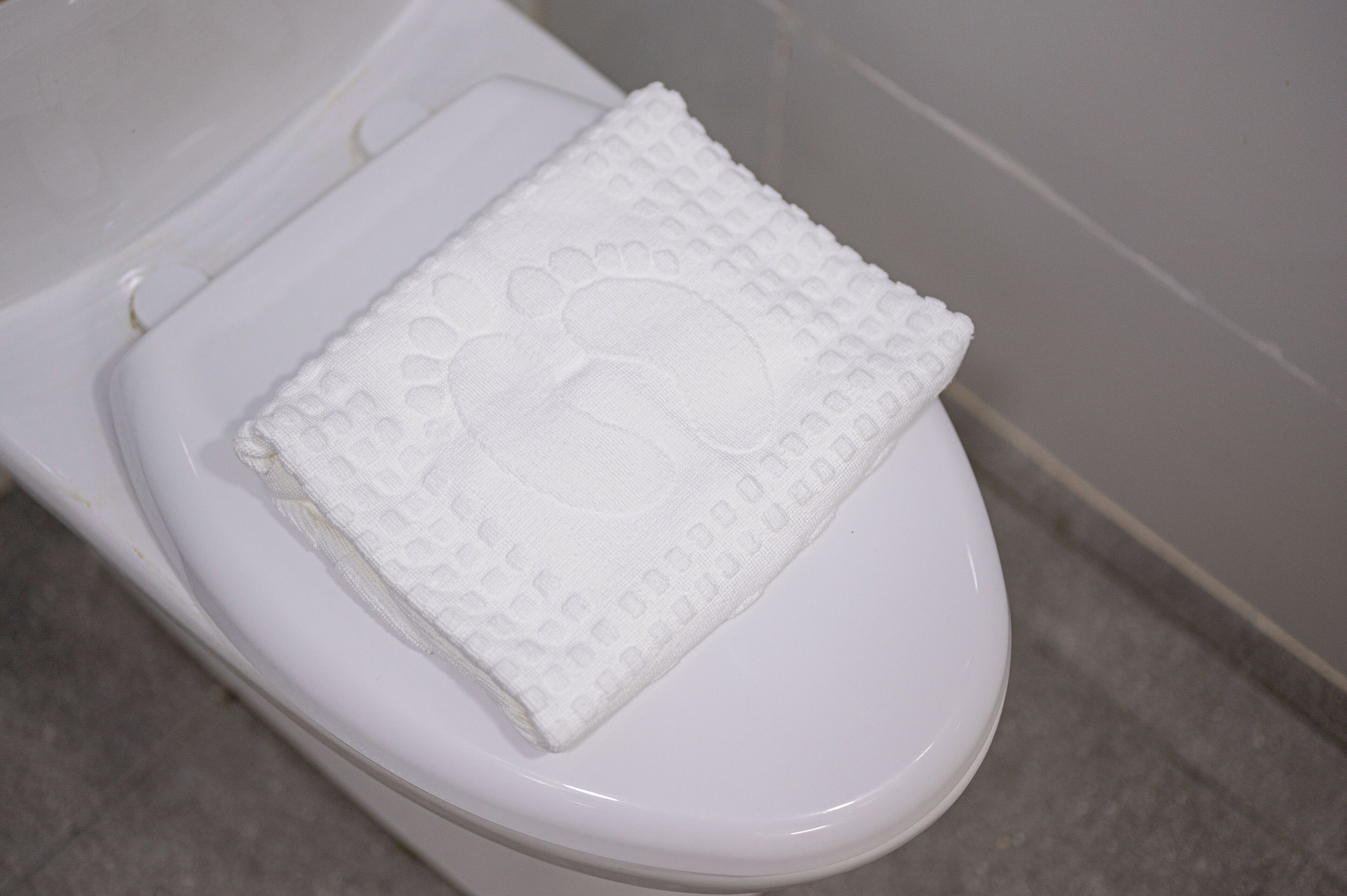 A white toilet with a textured seat cover.