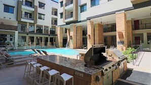 Un espace extérieur avec une piscine, un barbecue et des chaises longues.