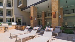 Un espace de détente aménagé sur le toit, avec des chaises longues, un coin barbecue et une vue sur l’intérieur du bâtiment.