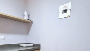 Zona pranzo con tavolo in legno, sedie e un bancone cucina con bollitore.