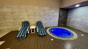 Relax in a serene spa area with two reclining chairs and a hot tub.