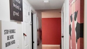 A hallway with motivational wall art, a red accent wall, and a ceiling light fixture. - 5 Rooms • Great Location • Red Haven Retreat (Tampa)
