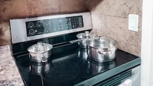 A kitchen with a stainless steel microwave and a black stove top with pots. - 5 Rooms • Great Location • Red Haven Retreat (Tampa)