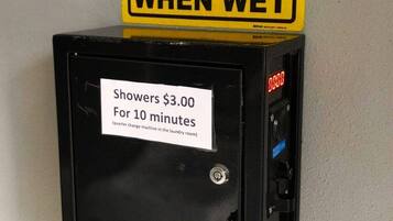 Schild mit Warnung vor Rutschgefahr bei Nässe und eine Münz-Dusche mit Preisschild.