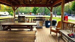 Ein überdachter Außenbereich mit Grill, Picknicktisch und Sitzgelegenheiten.