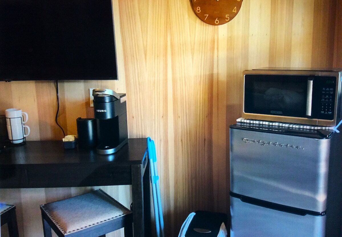 Una kitchenette equipada con microondas, cafetera y un reloj en la pared.