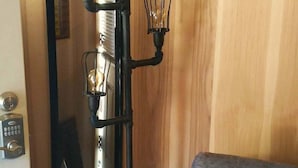 Een moderne kamer met een grote spiegel, een grijze bank en een zwart wandlamp met drie lampen.