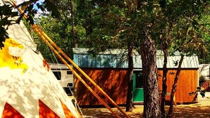 A campsite with a large tent, a small wooden structure, and a tree. - Sky Spirit -Luxury Glamping 18' Tipi -  Restrooms and Showers are only a short walk away. (O'Brien)