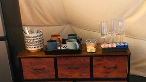 A wooden sideboard with drawers, a tray with cups and a box of tissues, and a white tent-like structure in the background. - Wild Horses Luxury Tipi -  Restrooms and Showers are only a short walk away. (O'Brien)
