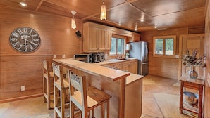 A wooden kitchen with a central island, wooden cabinets, a built-in stove, and a clock on the wall. - King (Flagstaff)