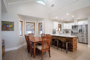 A spacious kitchen with white cabinets, stainless steel appliances, and a wooden island.