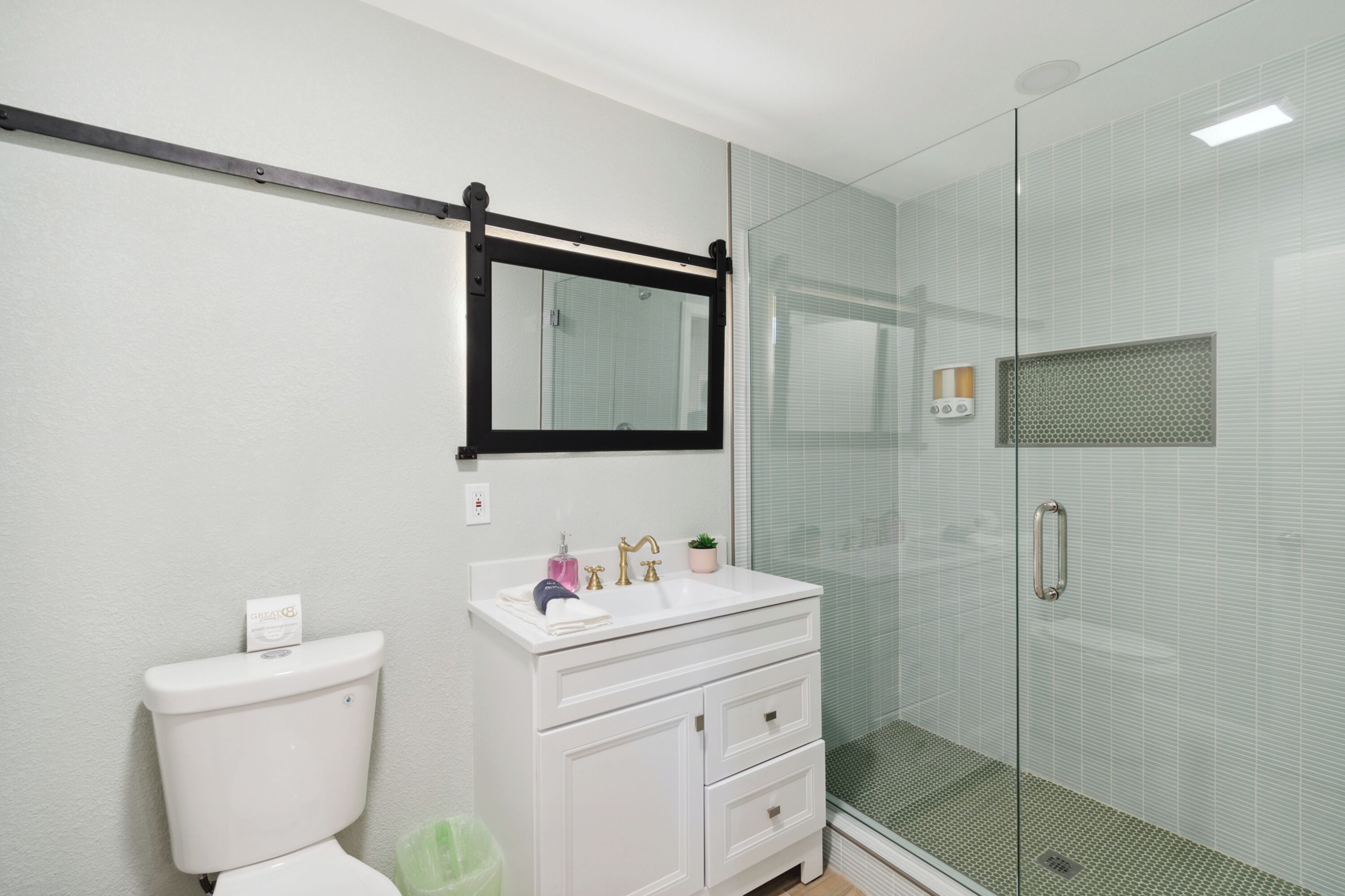 A bathroom with a white sink, a toilet, and a glass-enclosed shower.