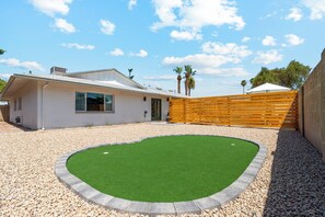 Een modern huis met een aangelegde achtertuin, met een gazon en een houten omheining.