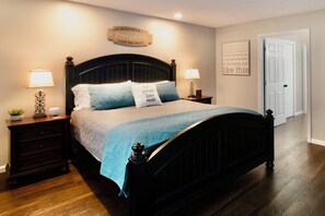 A bedroom with a dark wooden bed, two bedside tables with lamps, a wall with a sign, and a door. - "Relaxing Retreat" 7 Night Discount~No Stairs~Indoor Pool~Golf~Trout~Pickleball (Branson)
