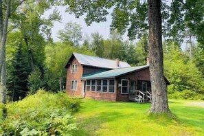 A wooden cabin with a green roof, surrounded by lush greenery and trees. - Clear Pond Cottage a Retreat on Private Pond (Hyde Park)
