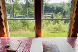 A room with a large window offering a view of a green landscape. - Clear Pond Cottage a Retreat on Private Pond (Hyde Park)