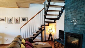 Una sala de estar con sofá, chimenea, televisor y una escalera.