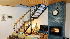 Una sala de estar con una escalera de madera, una chimenea y un árbol de Navidad.