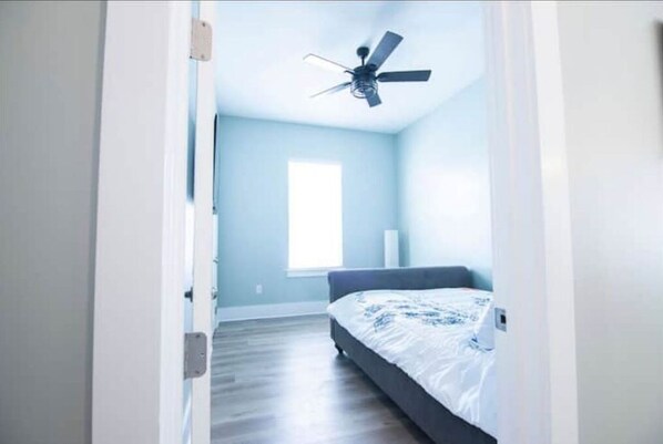 Une chambre à coucher avec un lit, un ventilateur de plafond et une fenêtre.