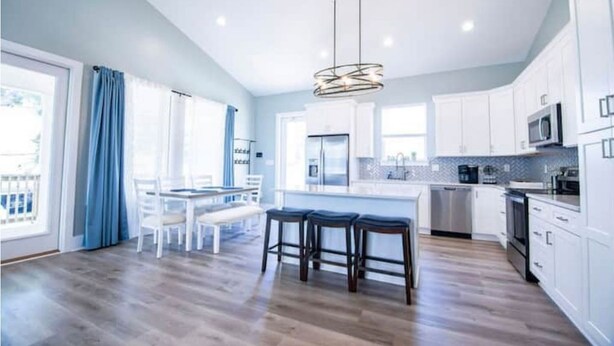 A spacious kitchen with white cabinets, a central island, and a dining area with a table and chairs.