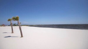 A beach with white sand and a clear blue sky.