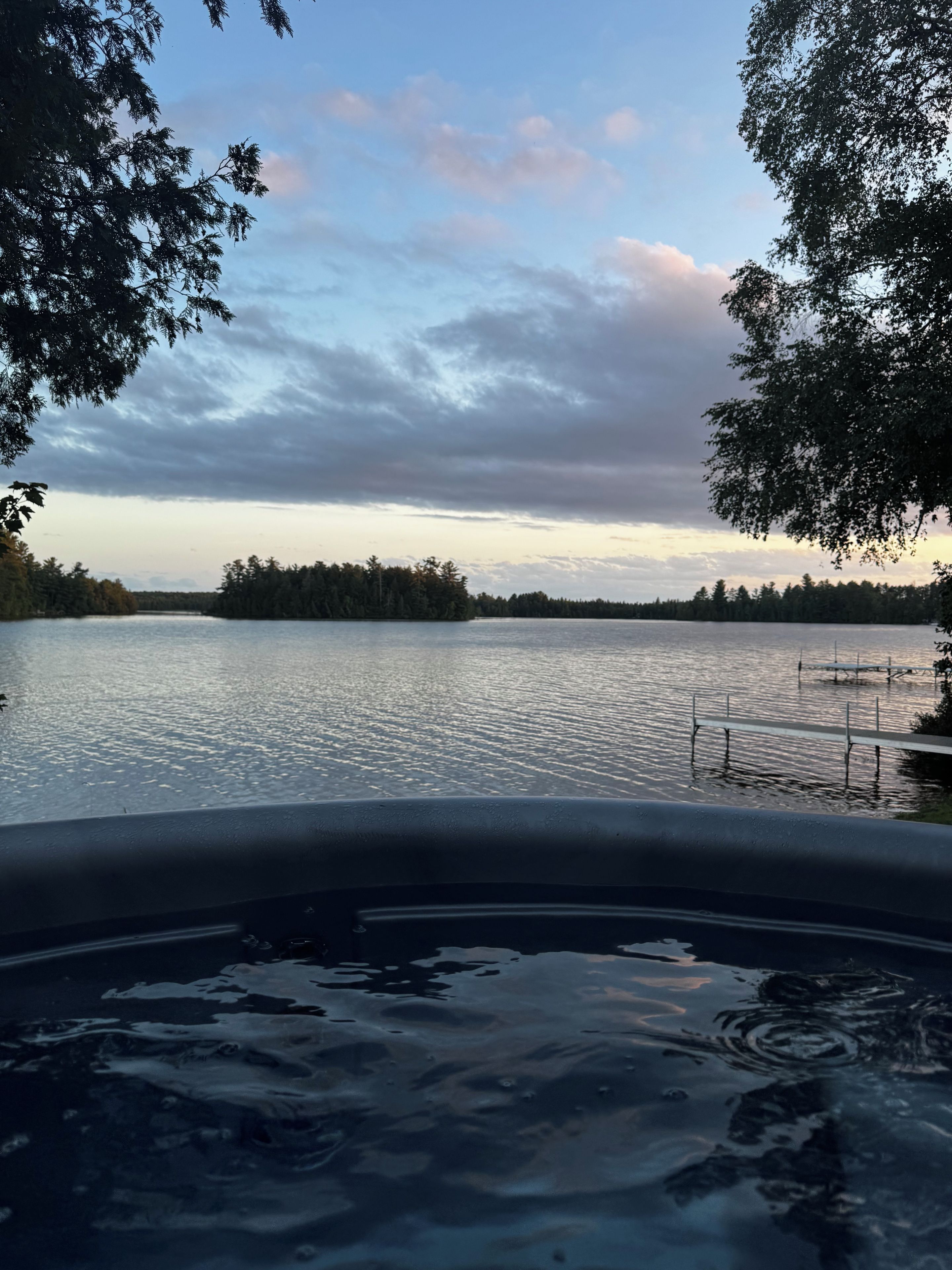 Ett bubbelbad med utsikt över en sjö och träd.