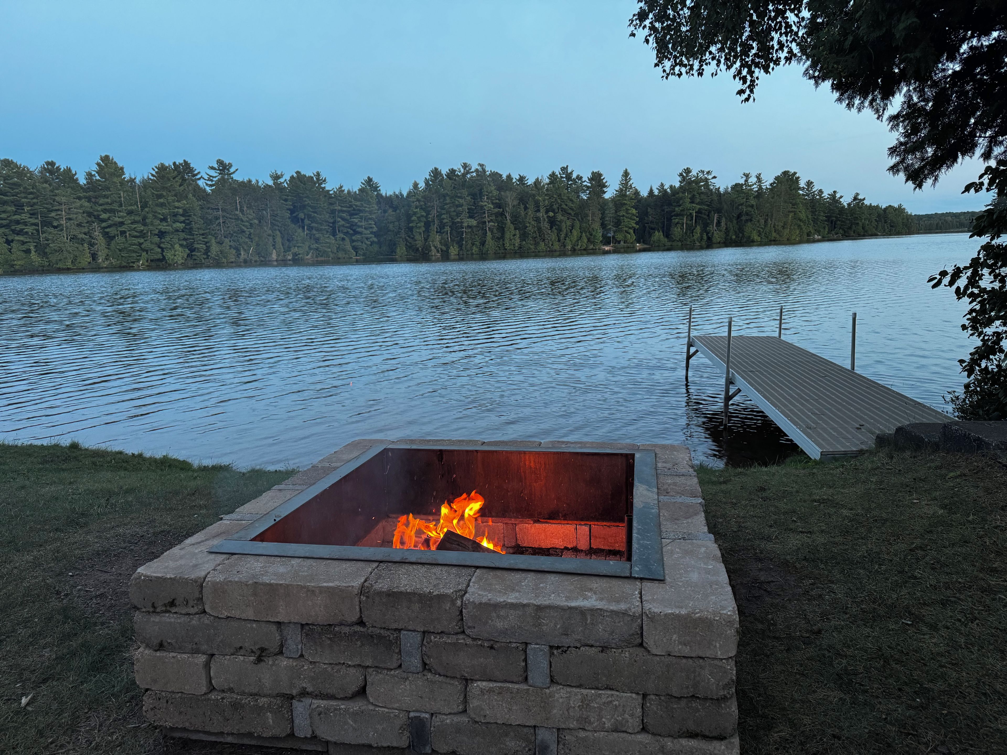 A fire pit with a view of a lake and forest.