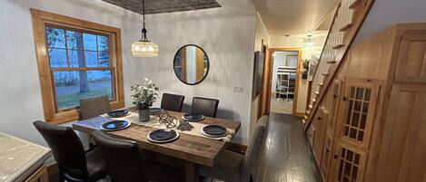 A dining area with a wooden table, chairs, and a hanging light fixture.