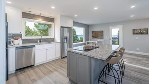A modern kitchen with a large island, stainless steel appliances, and a view to the outdoors. - Private Pool, Mountain Top Views & Home Theater (Hot Springs)