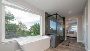 A modern bathroom with a large bathtub, a glass shower enclosure, and a view of the outdoors. - Private Pool, Mountain Top Views & Home Theater (Hot Springs)