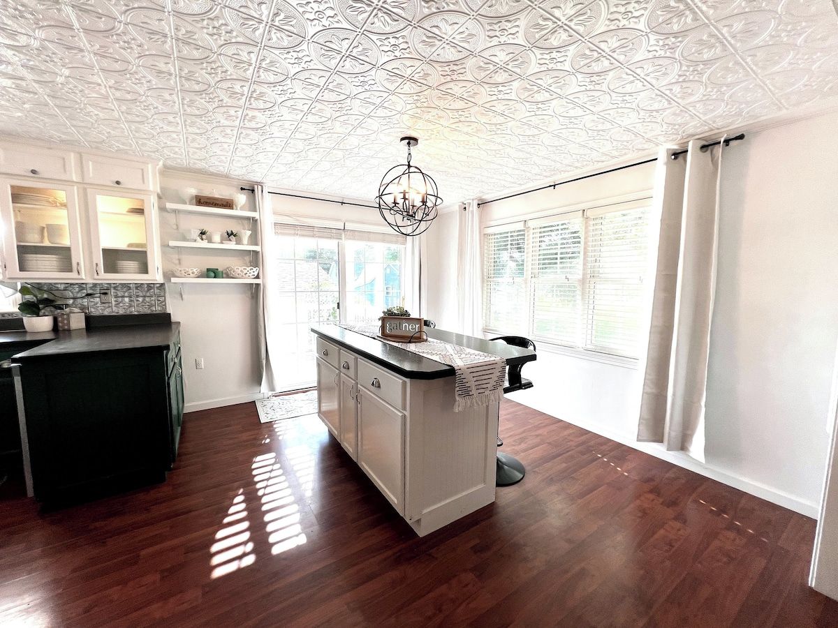 Une cuisine dotée d’un îlot central, de meubles blancs et d’un plafond décoratif.