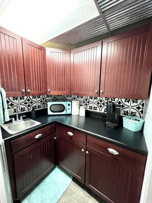 A compact kitchen with dark wooden cabinets, a stainless steel sink, a microwave, and a coffee maker. - Whole house in Norfolk, next to White Water Rapids (Norfolk)